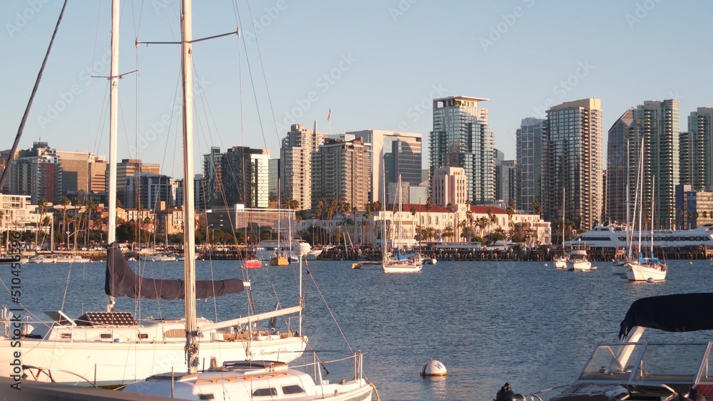 Yachts in marina and downtown city skyline at sunset, San Diego cityscape, California coast, USA. Highrise skyscrapers, boat in bay, waterfront promenade. Urban architecture and sailboat in harbor.