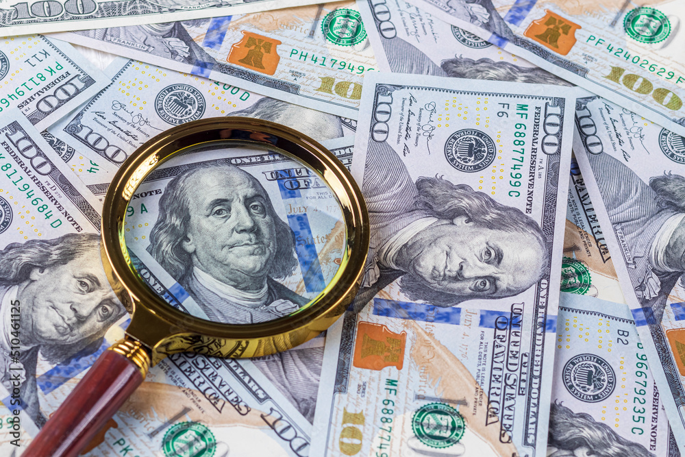 one hundred dollars. a magnifying glass in a gold frame. close-up