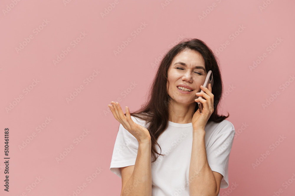 horizontal portrait of a funny woman in a white cotton T-shirt happily talking on the phone with her eyes closed. Photo on an empty background with space for an advertising layout horizontal portrait of a funny woman in a white cotton T-shirt happily talking on the phone with her eyes closed. Photo on an empty background with space for an advertising layout