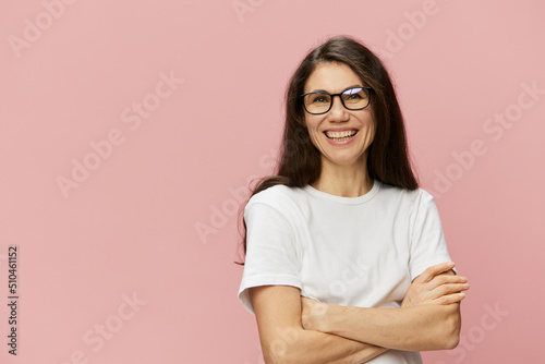 portrait of a cute, attractive brunette in a white tank top on a pink background, with a pleasant smile, standing in glasses for vision