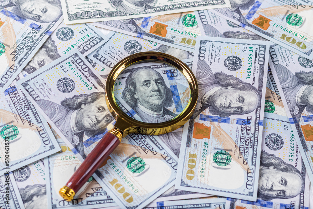 one hundred dollars. a magnifying glass in a gold frame. close-up one hundred dollars. a magnifying glass in a gold frame. close-up
