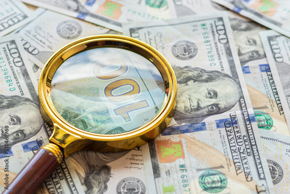 one hundred dollars. a magnifying glass in a gold frame. close-up