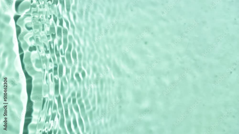 Single wave making ripples and splashes on water surface on green mint background | skin care background, sunscreen commercial Single wave making ripples and splashes on water surface on green mint background | skin care background, sunscreen commercial