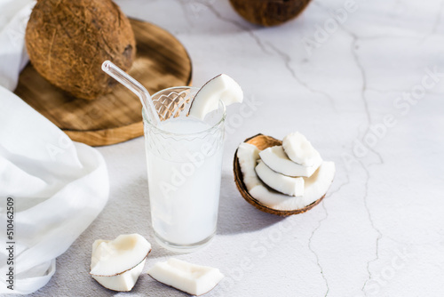 Coconut milk in a glass and pieces of tropical fruit on the table. Natural plant alternative