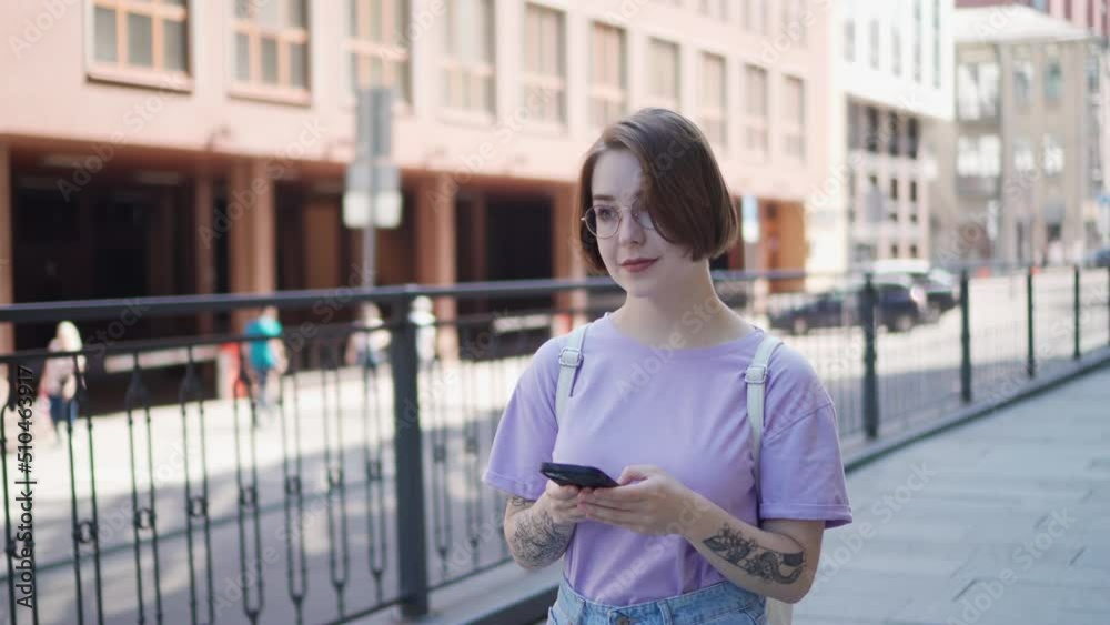 Young Pretty Girl Walks down Street with Phone and Typing Message