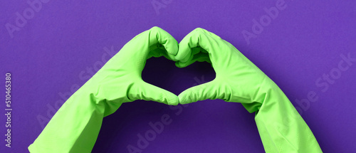 Billede på lærred Heart shaped hands in green rubber gloves over purple background