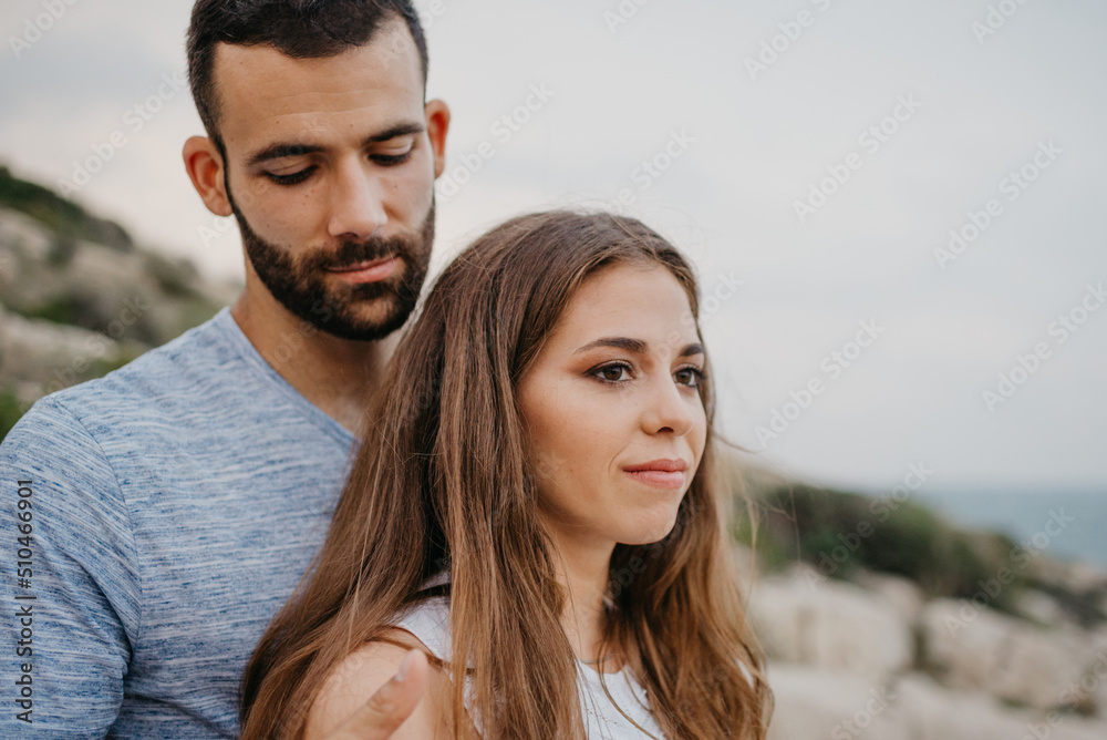 A close portrait of a Hispanic man who is hugging a Latina girlfriend on the rocky sea coast in Spain. A couple of tourists in the evening in a highland park in Valencia. A close portrait of a Hispanic man who is hugging a Latina girlfriend on the rocky sea coast in Spain. A couple of tourists in the evening in a highland park in Valencia.
