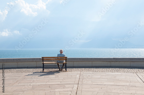 The old man sits on the bench and watches the sea.. © stdemiriz