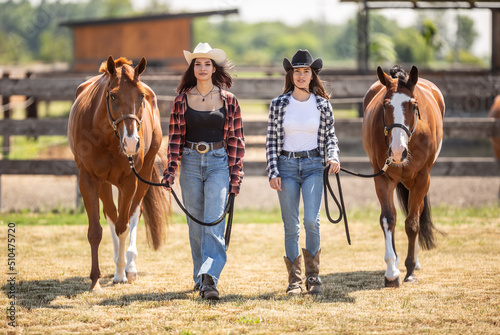 Two cowgirls confidently walk their paint horses towards the camera
