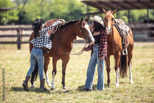 Women saddling up their horses on a ranch before riding them