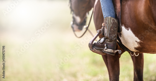 Detail of a ornamented cowboy boots in a stirrup while sitting on a horse