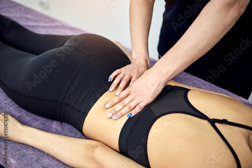 Close up of Physiotherapist massaging a female patient sportswoman with damaged muscles in kinesio clinic. Treatment of sports injuries.