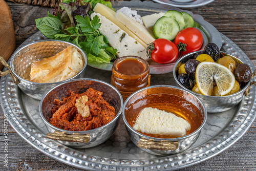 Healthy traditional Turkish breakfast, scrambled eggs with sausage ,cheeses ,olives ,tomatoes ,cucumbers.etc. served on a tray with tea