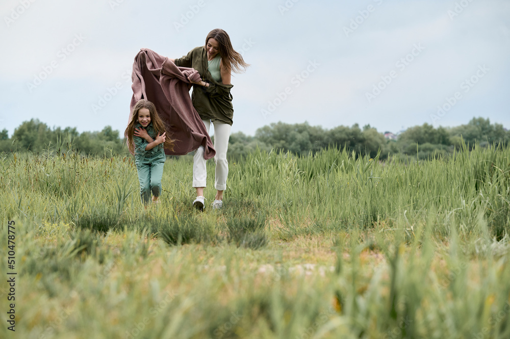 young beautiful mother playing with her little daughter by the river in nature young beautiful mother playing with her little daughter by the river in nature