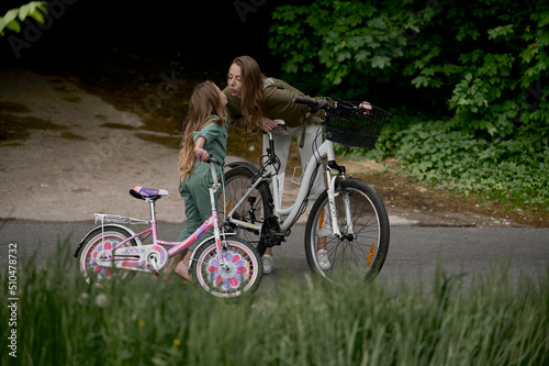 Mom and daughter cycling in the park. Children summer vacation concept © jul14ka
