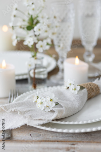 Rustic zero waste wedding decor with natural elements. Wooden table, candles, linen napkins, branches with green leaves. Eco-friendly decoration for the special dinner. Romantic and cozy place