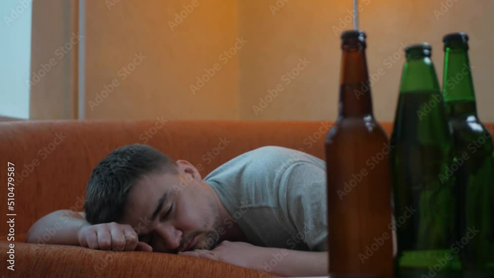 Young sleepy man waking up in bed after alcohol abuse and drug