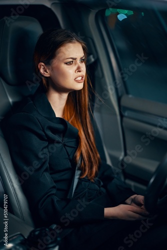vertical portrait of a frustrated woman sitting in a car at night behind the wheel wearing a seat belt © SHOTPRIME STUDIO