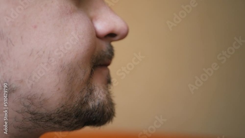 Close up of badly shaved male drinking alcohol with pleasure licking his lips and savoring every sip. Young male drinking tasty beer and enjoying a day off. Alcoholism concept. Guy tasting beer photo