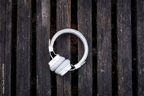 White headphones on a wooden background, flat lay.