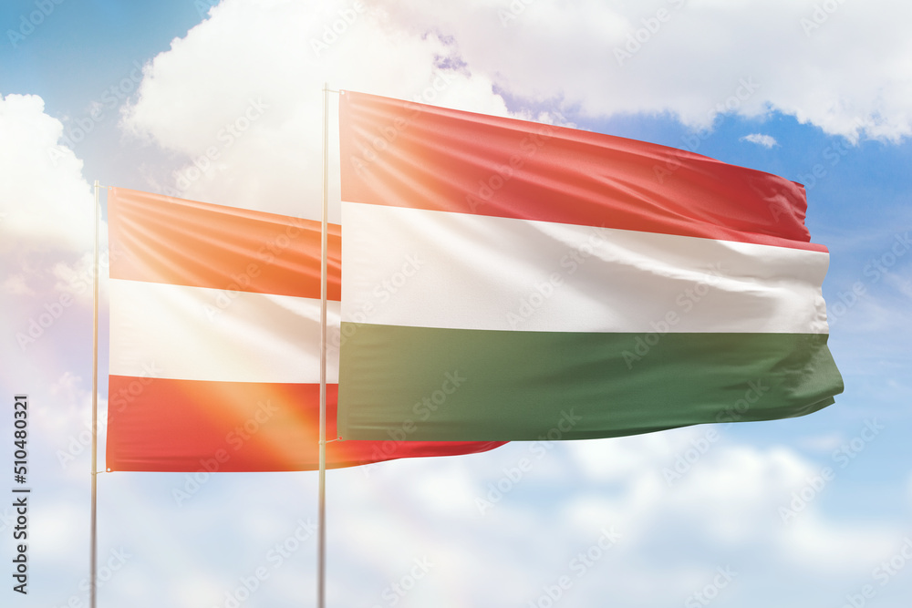 Sunny blue sky and flags of hungary and austria Sunny blue sky and flags of hungary and austria