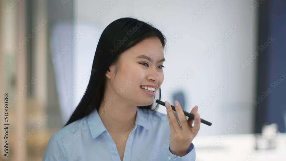 Young asian woman recording voice message to friends, talking to mobile app on smartphone at office, slow motion Young asian woman recording voice message to friends, talking to mobile app on smartphone at office, slow motion