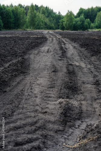 Country road through a plowed agricultural field. Farming and food industry. Photo background