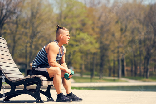 Young athlete sitting on bench with weights
