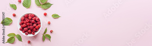 Banner Fresh raspberries in white bowl and green leaves on pastel pink background. Flat lay, top view, copy space