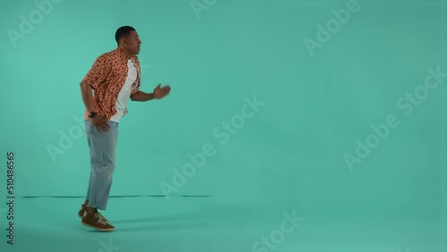 Expressive dark-skinned man running on same spot pretending to be in a hurry. Man looking at wrist watch and speeding up to not be late for discounts or sales, studio shot isolated on background photo