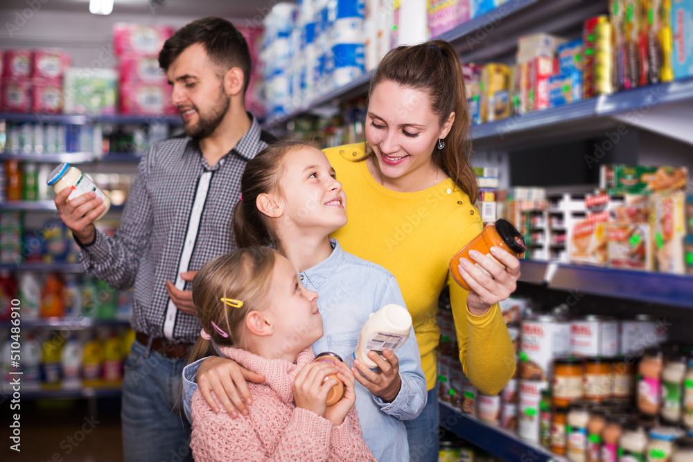 portrait of young positive family of four shopping together in grocery store