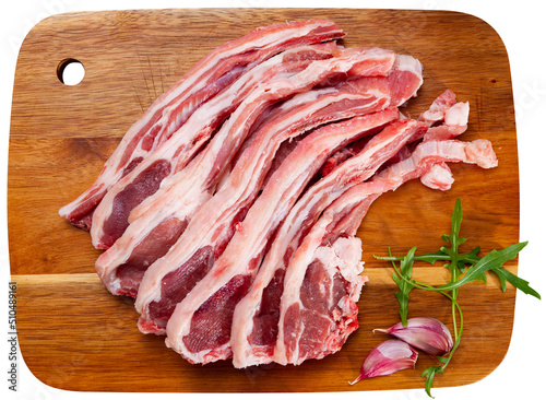 Sliced fresh raw lamb for chops, garlic and herbs on a chopping board. Ingredients for cooking. Isolated over white background photo