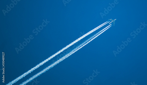 Canvas Print Airplane with a long reverse trail in the blue sky