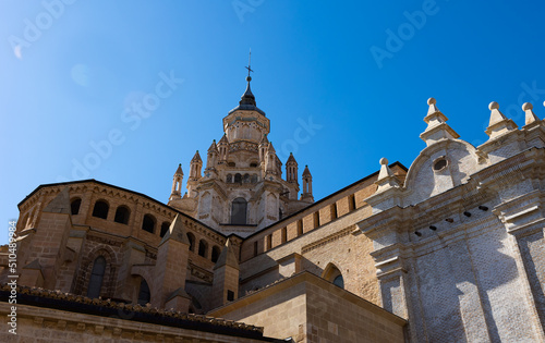 Impressive architecture of ancient Roman Catholic Cathedral Santa Maria de Huerta in Tarazona with dome tower decorated with turrets in Aragonese Mudejar style against blue sky on sunny day, Spain