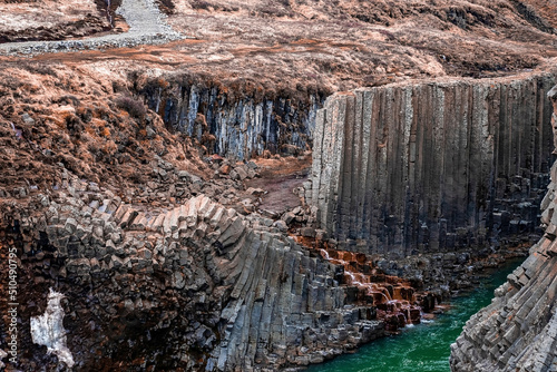 Scenic view of stream flowing amidst basalt columns formation. Beautiful rocky cliffs at Eastfjords in valley. Idyllic scenery of famous tourist attraction in volcanic landscape. photo