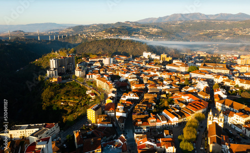 Picturesque drone view of Vila Real cityscape in valley framed by Alvao and Marao mountain ranges in light fog with suspension viaduct crossing Corgo River in background on sunny spring day, Portugal photo