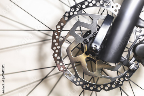 Front hydraulic disc brake on a mountain bike on a black fork and spokes from the wheels, close-up