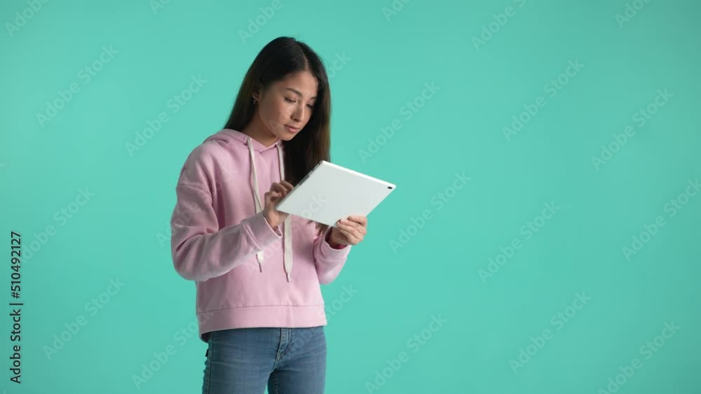 Thoughtful young woman with tablet thinking over idea, smiling satisfied with right decision and frowning when idea slips away. Portrait of pensive asian girl working on project isolated on background Thoughtful young woman with tablet thinking over idea, smiling satisfied with right decision and frowning when idea slips away. Portrait of pensive asian girl working on project isolated on background