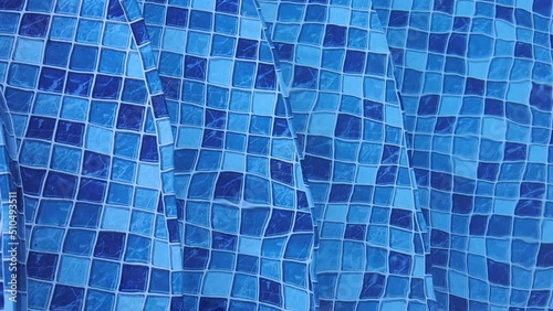 Água de piscina com pequenas ondas. Água em movimento em uma piscina de vinil com mosaico cheio de quadrados em diferentes tons de cor azul. Degraus de piscina. Verão, Calor, Lazer. photo