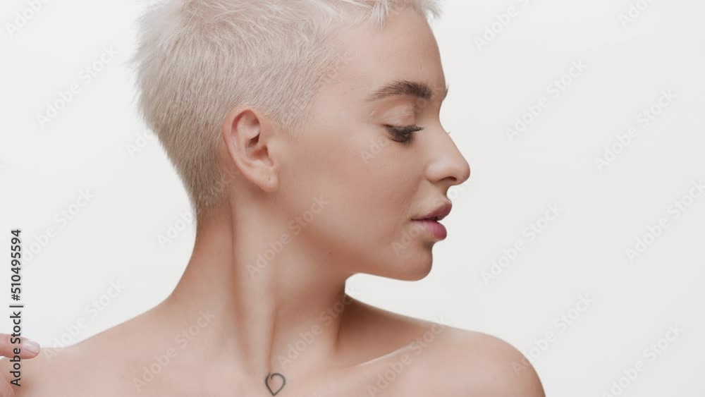 Gorgeous young slim Caucasian woman with light hair strokes her collarbones turning her head on white background | Body moisturizing concept Gorgeous young slim Caucasian woman with light hair strokes her collarbones turning her head on white background | Body moisturizing concept