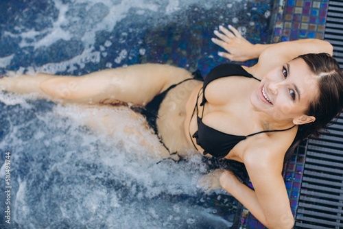 A beautiful fashionable woman in bikini posing on jacuzzi background