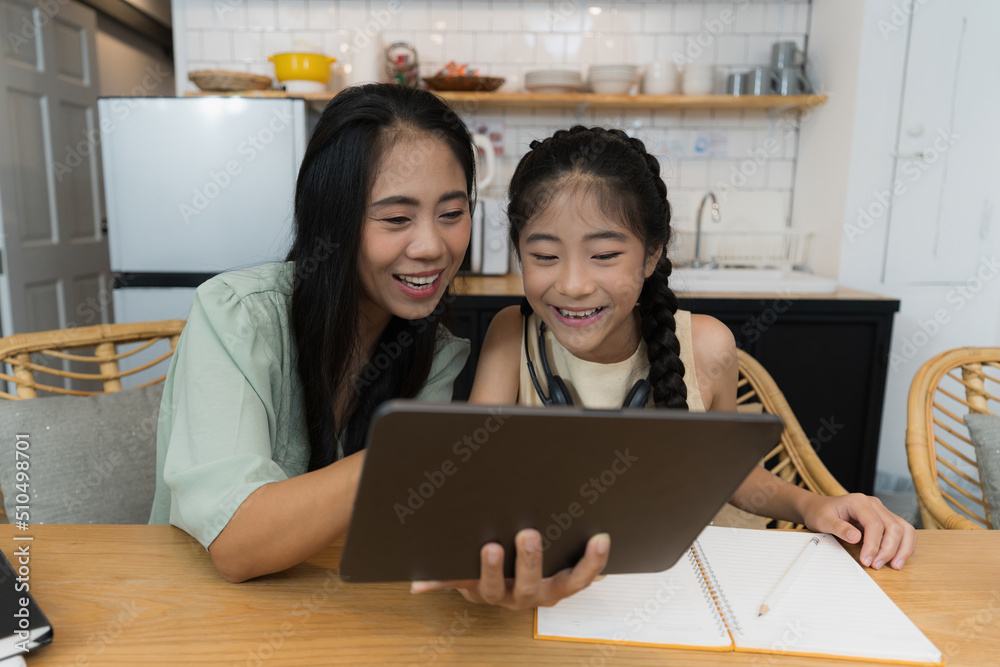 Family and home school concept. Asian mother teach her daughter using application on digital tablet at home. Family and home school concept. Asian mother teach her daughter using application on digital tablet at home.
