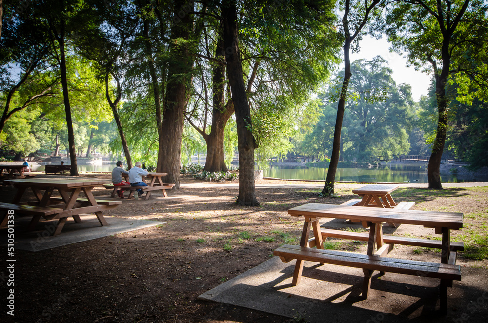 latinos mexicanos, padre e hijo desayunando en las bancas de un parque, frente a un lago por la mañana