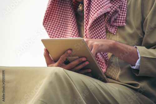 Islamic man using smartphones app organize schedule agenda  focus on hands holding smartphone muslim modern uae city. Arab men wear hijab and muslim formal dress sending text sms online lifestyle photo