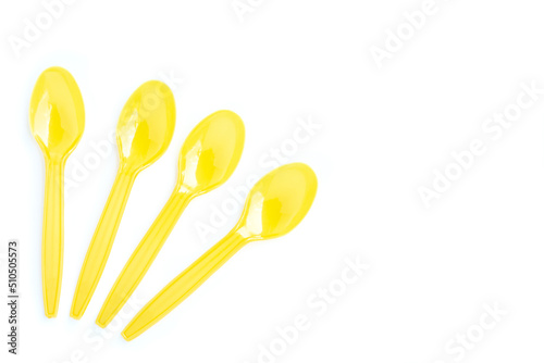 Yellow plastic spoons on white background
