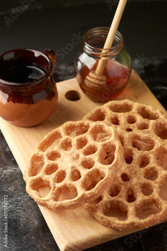 Mexican buñuelos or puñuelos with a circular shape, at the bottom coffee and honey to enjoy, placed on a wooden base. photo