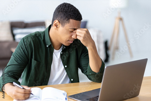 Fotografija Close-up portrait of tired stressed African American man having headache feeling sick