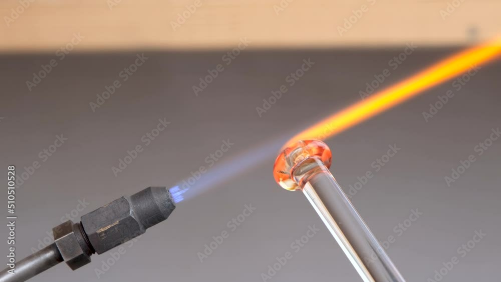 Close-up craftsman hands working to create glassware. Glassmaker heating the glass for forming with at high temperature flame. Making pearl or glass bead, with the ancient technique. 4k, slow motion. Close-up craftsman hands working to create glassware. Glassmaker heating the glass for forming with at high temperature flame. Making pearl or glass bead, with the ancient technique. 4k, slow motion.