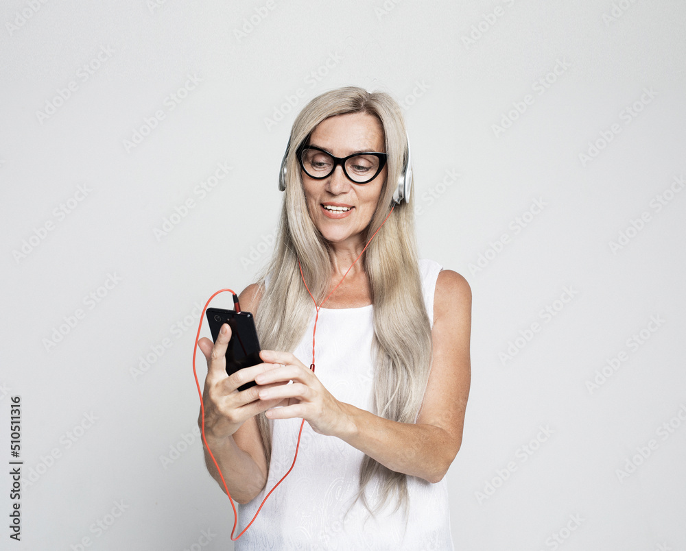 happy old woman with long white hair wearing eyeglasses listening to music with headphones