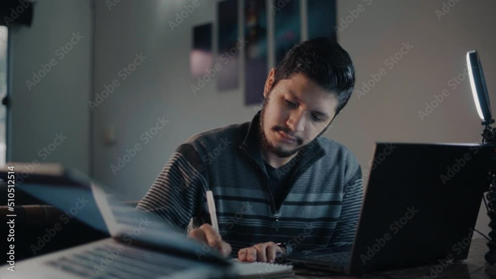 Young man taking notes from his virtual class Young man taking notes from his virtual class